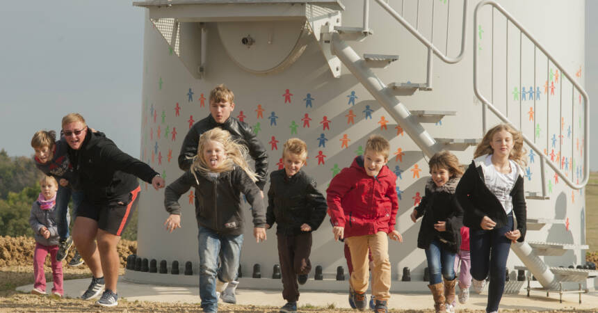 Des enfants sociétaires des Ailes des Crêtes courent au pied de l'éolienne citoyenne des enfants ! (Photo : Carl Hockart / Enercoop)